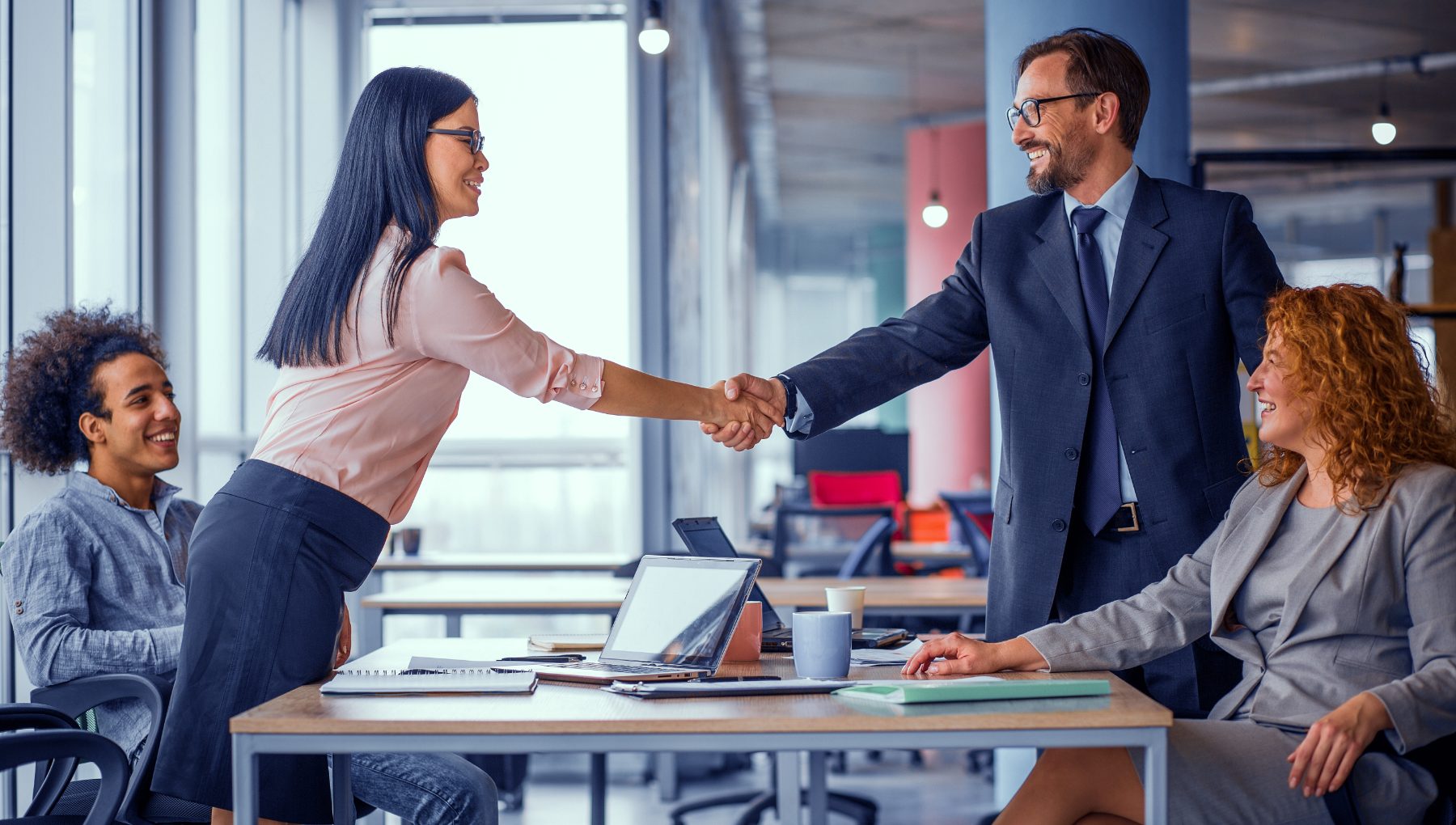 A service provider shaking hands with a client across a meeting table